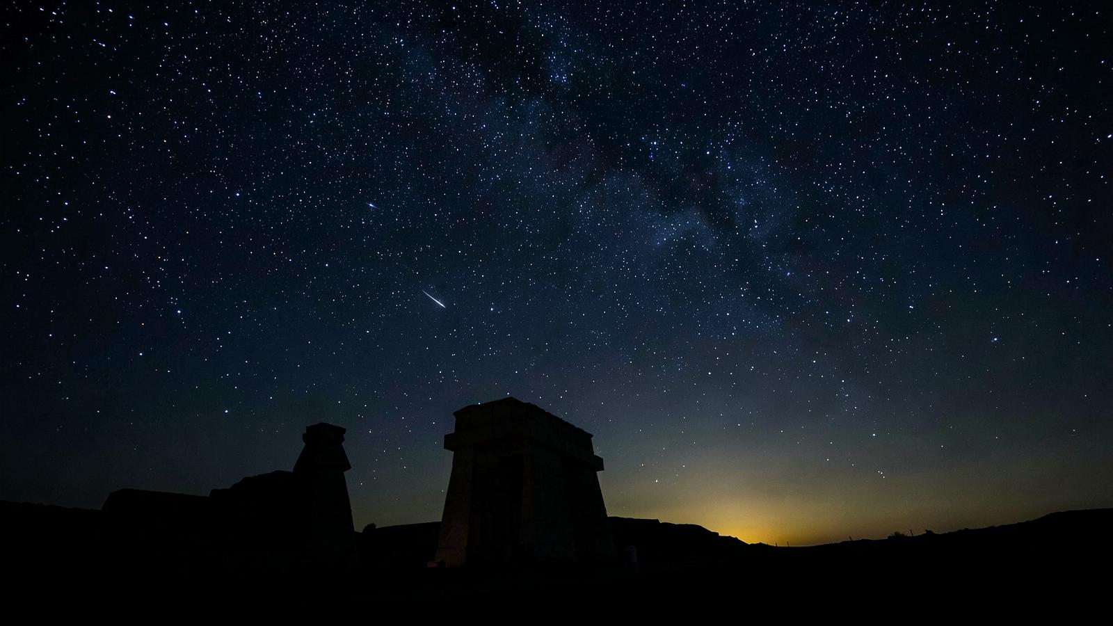 Stars above the silhouette of a temple pylon at night